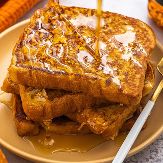 Three perfectly golden slices of French toast, generously drizzled with Lyle's Golden Syrup, served on a plate.