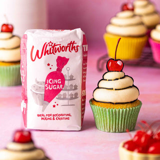 A bag of Whitworths icing sugar next to a vibrant comic-style cupcake with bold swirls of frosting and a bright red cherry on top, outlined in thick black lines for a playful, cartoonish look.