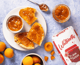 Homemade apricot jam on toast, surrounded by a jam jar and fresh apricots