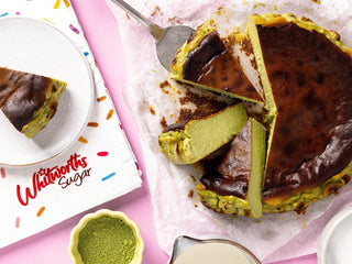 A perfectly caramelised matcha basque cheesecake with a soft custardy centre with slices taken out of it ready to be served
