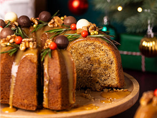 A wreath shape cake decorated with salted caramel drizzle, walnuts and chocolates