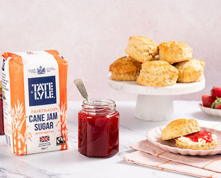 Tate & Lyle jam sugar on a counter with homemade strawberry jam and fresh scones