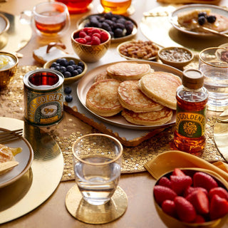 Pile of pancakes served with fruits and Lyle's golden syrup
