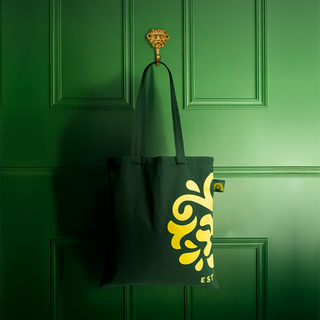 Black tote bag with yellow logo on a green door