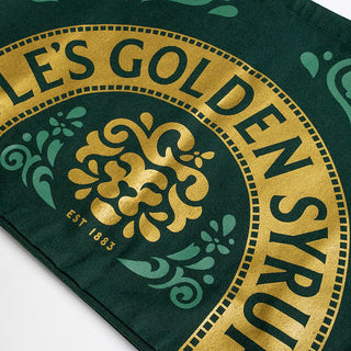 Close-up of a green and gold label with decorative elements on a fabric background