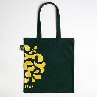 Green Lyle's Golden Syrup tote bag with yellow floral design and '1883' text on a green background