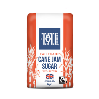 A 1kg bag of Tate & Lyle Fairtrade Cane Jam Sugar with Pectin, featuring a white and orange design with illustrations of sugarcane leaves and a blue brand logo.