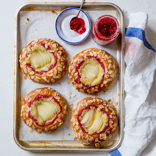 Pear & Raspberry Jam Brioche Tarts topped with sliced pears, almond flakes, served with raspberry jam on the side.