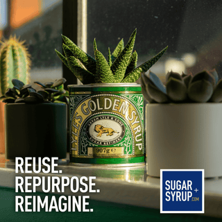 A green and gold can of Lyle's Golden Syrup repurposed as a planter for a small succulent, displayed on a windowsill with other potted plants in a real environment. Text overlays read 'REUSE.